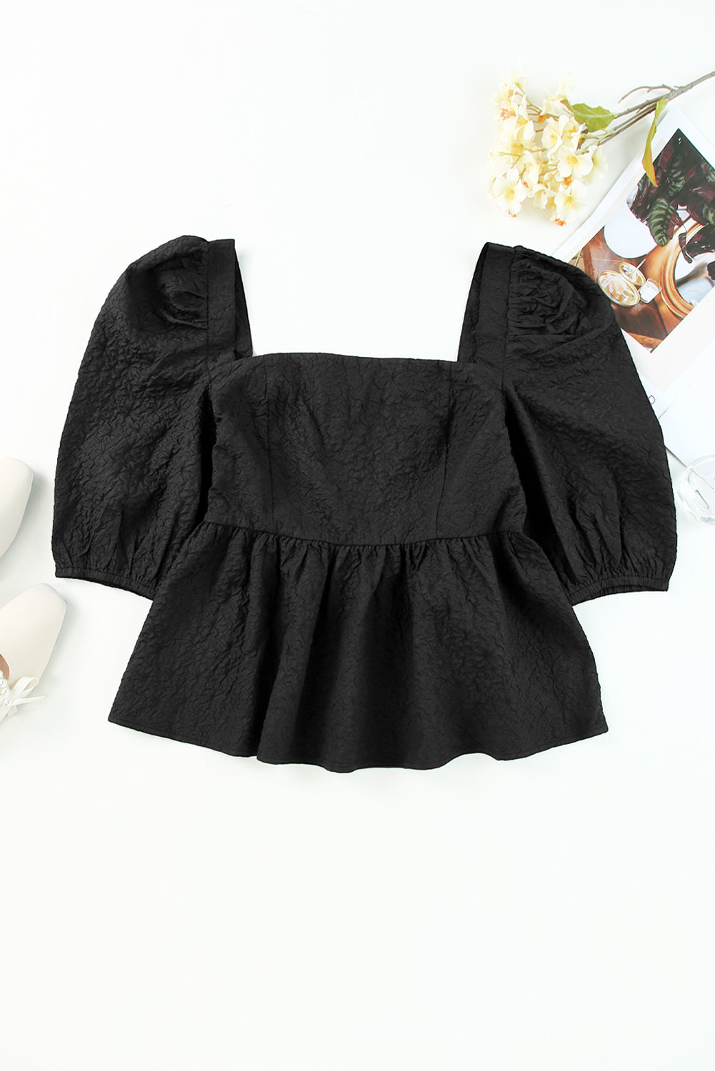 Blouse péplum noire texturée à col carré et manches bouffantes