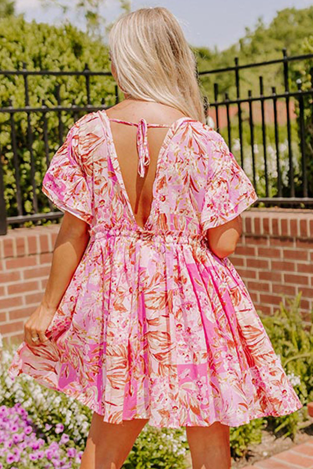 Robe florale rose avec nœud papillon et dos ouvert, col en V